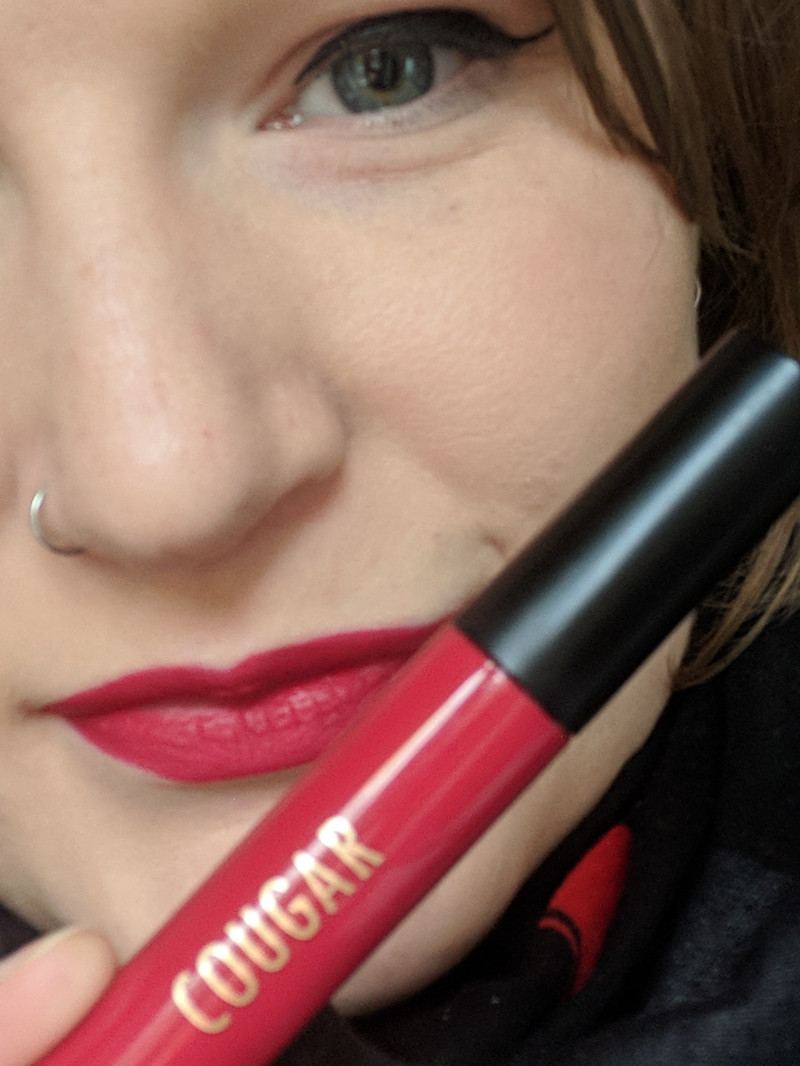 Woman holding red Cougar lipstick to her face