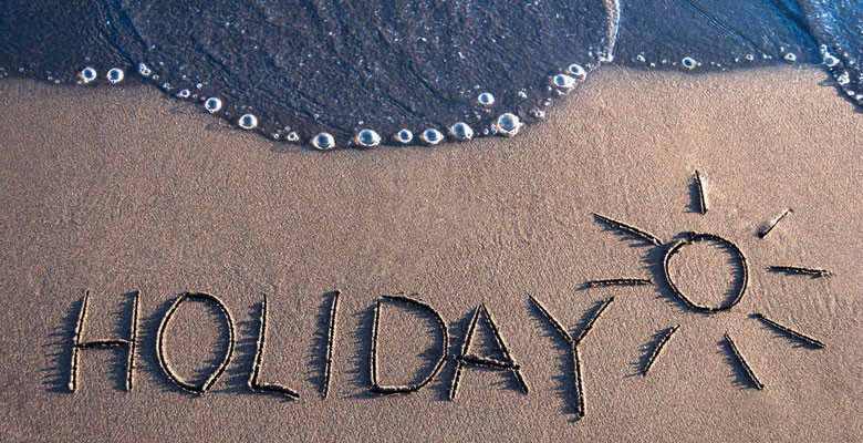 'Holiday' written on the sand with sea on the edge - photo taken from bird's eye perspective