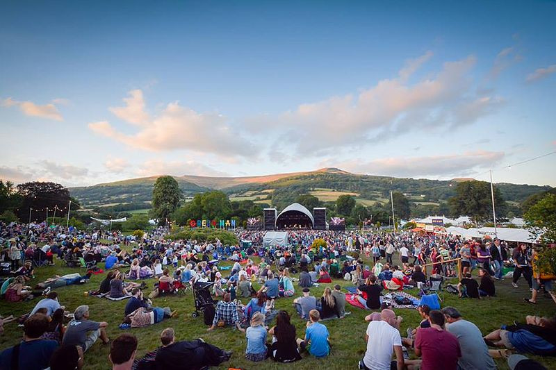 Sunset at Green Man Festival, crowds of people sat down watching a stage