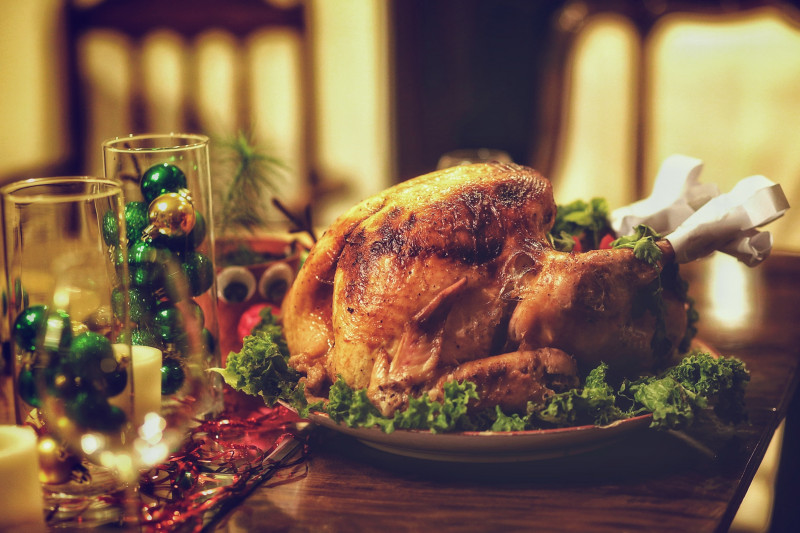 Cooked turkey on a decorated Christmas table, with 2 clear glasses filled with green baubles