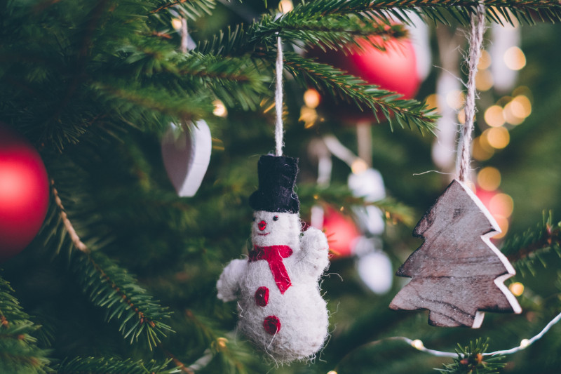 Close up of Christmas decorations hung up on Christmas tree, including snowman and wooden Christmas tree