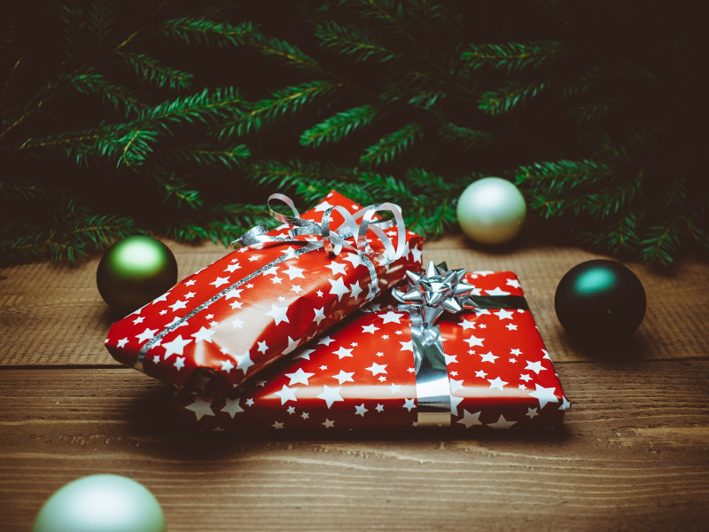 Two presents wrapped in red starry Christmas paper, underneath a green Christmas tree