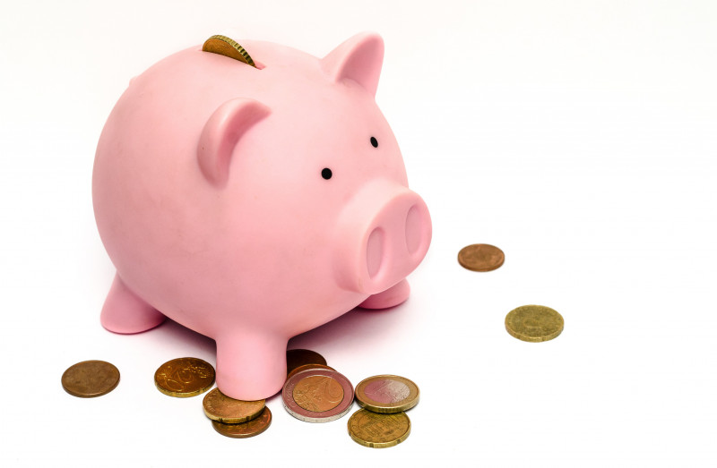 Pink piggy bank with coins around, on a white background