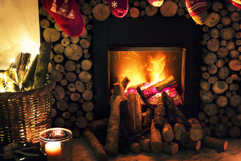Fire place surrounded by wooden sticks and with stockings hanging on the fireplace