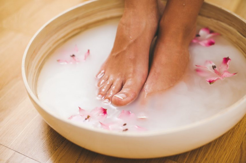 Pair of feet soaking in a bowl with flowers in
