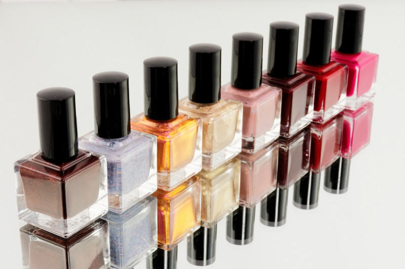 Eight nail varnishes in an array of colour line up on a mirrored background