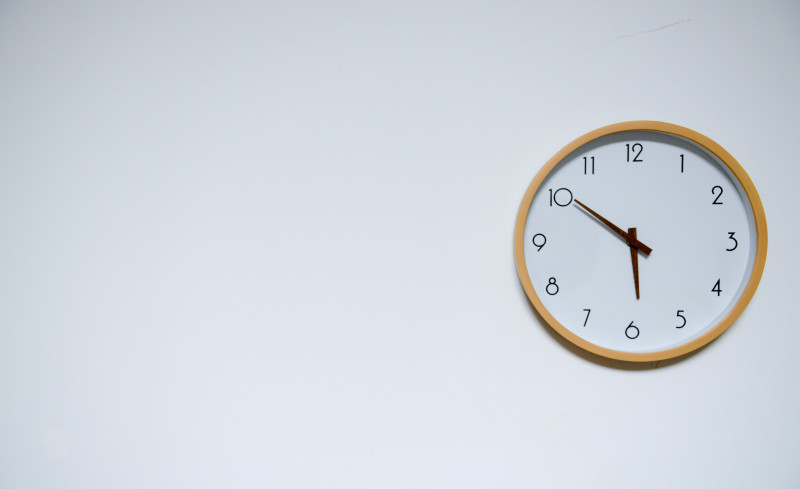 Clock face on a white wall at 5:50