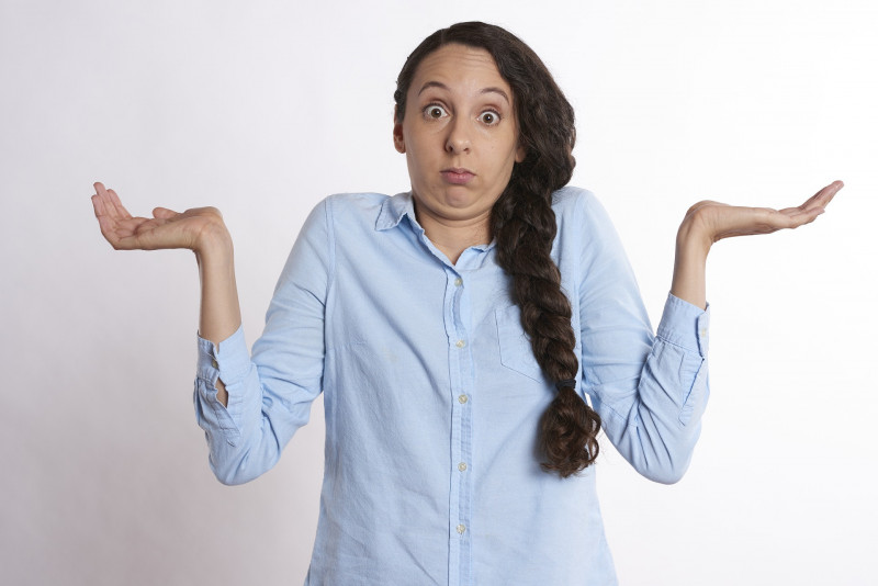 Brunette woman wearing blue shirt shrugging her shoulders