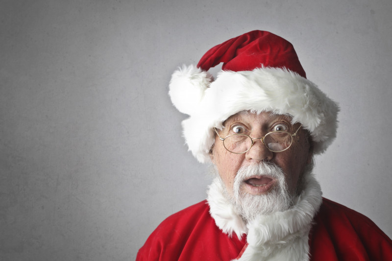 Close up of Santa wearing red hat with white fur trim against a white background