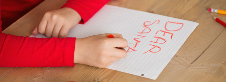 Close up of child writing a letter to Santa in red crayon