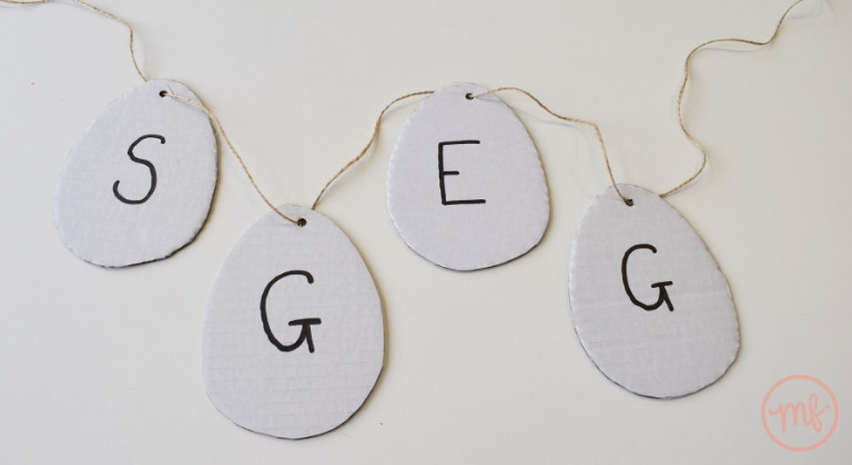 White cardboard shaped like eggs with the word 'EGGS' written on, jumbled up in order