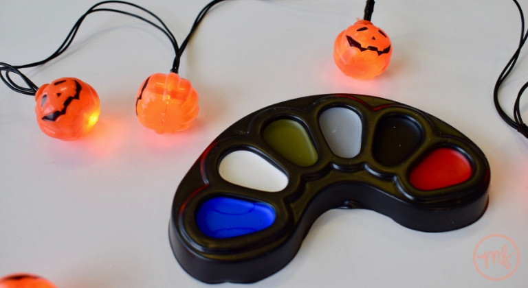 Close up of face paints with pumpkin lights behind