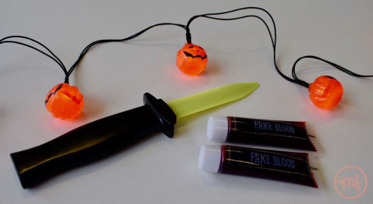 Retractable toy knife and two tubes of fake blood on a white table